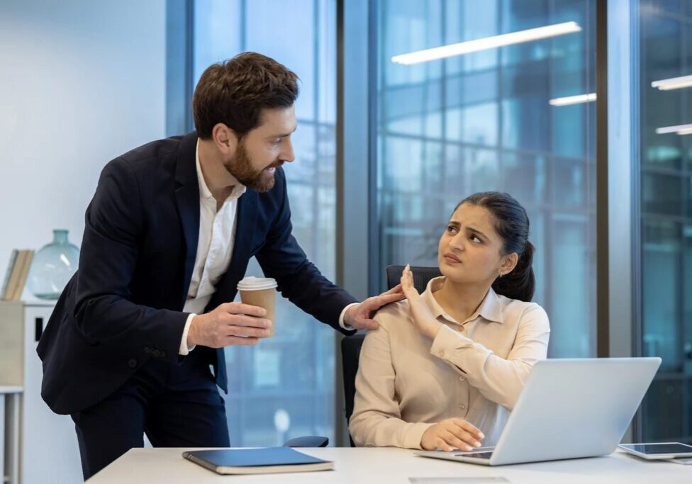 Office confrontation between coworkers near laptop.