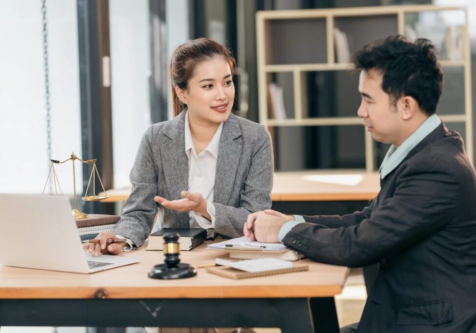 Two professionals discussing at office desk.