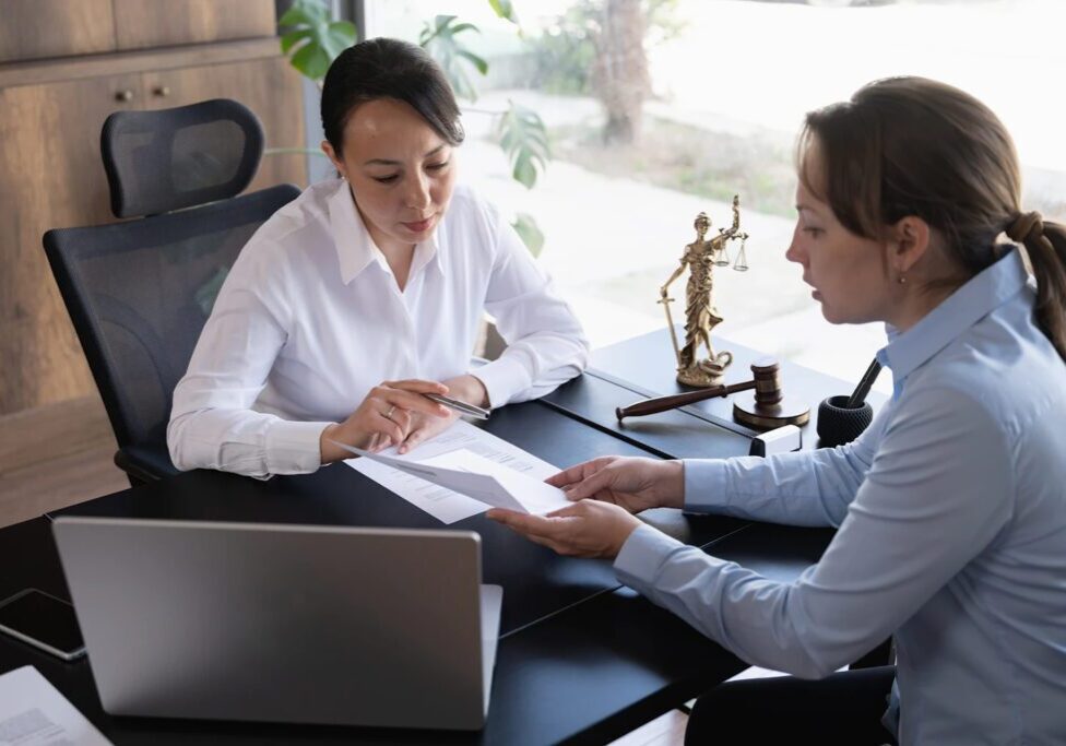 Two women discussing documents in office.
