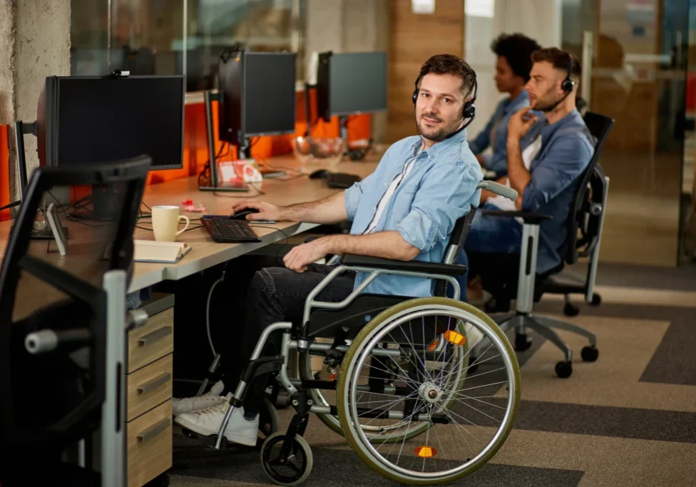 Man in wheelchair working at office desk.