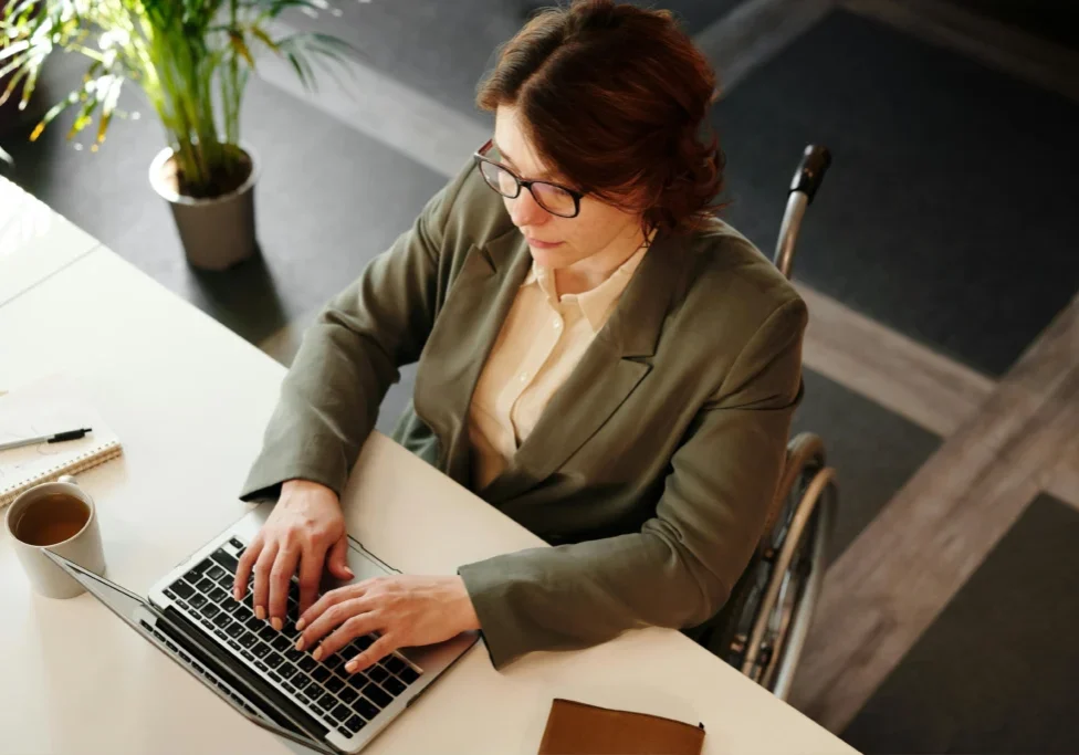 Person in wheelchair working on laptop.